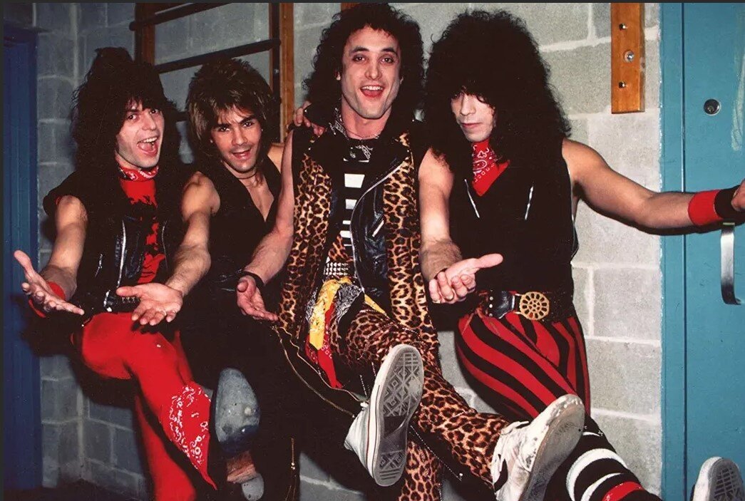 Личный состав Quiet Riot производит физическое упражнение: приседание на одной ноге. Делай раз!