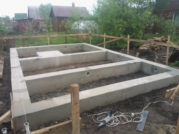 Ленточный фундамент для баниПри устройстве ленточного фундамента важно помнить, что его высота над уровнем земли зависит от материала стен и уровня залегания грунтовых вод.  В общем случае она варьируется в пределах 20-40 см. Для устройства основания нельзя использовать силикатный кирпич, поскольку он хорошо впитывает влагу и со временем разрушается. Ширина ленты может быть от 25 до 50 см и зависит от материала стен.