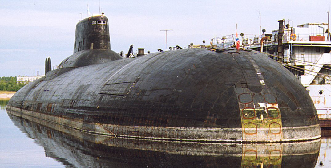 Самая большая в мире атомная подводная лодка (АПЛ) ТК-208 «Дмитрий Донской» проекта 941 типа «Тайфун» – прообраз суперсовременной советской субмарины из романа американского писателя Тома Клэнси «Охота за «Красным Октябрем» 
«Дмитрий Донской» – последний корабль 941-го проекта, входящий в состав Военно-морского флота. Его постоянным местом дислокации считается Беломорская военно-морская база в Северодвинске. АПЛ решает задачи испытания новых типов морских вооружений и техники. С ее борта проводились практически все испытательные пуски новейшей морской баллистической ракеты «Булава». Кроме того, «Дмитрий Донской» привлекается к испытаниям новейших стратегических и многоцелевых субмарин 955-го и 885-го проектов типа «Борей» и «Ясень». 

Роман «Охота за «Красным Октябрем» появился в 1984 году. В то время головной «Тайфун» только поступил на вооружение Северного флота. Его облик был строго засекречен. СССР построил лодку, не имеющую аналогов как по боевым возможностям, так и по составу вооружения. Но, несмотря на секретность, снимок «Тайфуна» в сдаточном доке попал в английский журнал Jane’s Defence. Сделала его якобы крановщица Северодвинского машиностроительного предприятия. КГБ вычислило ее по ракурсу, с которого был снят секретный объект. Так взорвалась «бомба». 



Вряд ли, работая над романом, Клэнси знал о существовании лодки 941-го проекта. Главный герой его произведения – советский командир подлодки «Красный Октябрь» Марко Рамиус (в одноименном фильме его играет Шон Коннери) по сюжету принимает решение перейти на Запад вместе со своим уникальным кораблем и его командой. Он хочет предотвратить ядерную войну между СССР и США, передав противнику новейшие советские технологии: на лодке установлена система, делающая ее практически незаметной для акустических станций. Но появление снимка придало и роману, и фильму особую остроту. 

ТК-208 и сегодня будоражит сознание своими размерами. Его полное водоизмещение составляет почти 50 тыс. т. Длина – 173 м, ширина – 23 м. Это позволяет развернуться на его палубе грузовому автомобилю КамАЗ. В его носовой части размещаются 20 самых мощных баллистических ракет РСМ-52 (уничтожены в рамках российско-американского Договора СНВ). Эти машины несли по десять ядерных боеголовок индивидуального наведения. За свои циклопические размеры и ударную мощь на Западе корабль получил название Typhoon. 

Внутри легкой (внешней) надстройки, покрытой специальным погашающим гидроакустический сигнал покрытием, находятся пять прочных корпусов. В них размещены сауна, бассейн, спортивный зал и самое необычное – каюта для курения, которой нет ни на одной другой подлодке мира. Между двумя главными корпусами – пусковые шахты баллистических ракет. В носовой части лодки расположены шесть торпедных аппаратов, через которые можно стрелять торпедами, подводными скоростными ракетами и ставить мины.

Но, пожалуй, главным и самым неприятным для Запада открытием стало то, что в отличие от всех других советских АПЛ «Тайфун» мог, не обнаруживая себя, произвести пуск ракет из-под многометровой ледяной полярной шапки. Другим АПЛ для этого приходилось перед пуском проламывать корпусом лед, создавая полынью, и тем самым выдавать свое местонахождение. «Тайфуну» она была не нужна. Заняв боевое положение и получив сигнал на применения оружия, экипаж производил пуск ракет. Но перед тем как стартовать, первыми к поверхности устремлялись реактивные снаряды, разбивавшие многометровый лед, и только следом за ними стартовали баллистические ракеты. 

Из-за этой особенности 941-й проект нельзя было обнаружить из космоса, а значит, и предотвратить нанесение ракетного удара. Несмотря на столь высокий боевой потенциал, на флоте «Тайфун» невзлюбили, презрительно обозвав его «водовозом». По соотношению водоизмещения и перевозимого груза (баллистических ракет) 941-й проект  проигрывал другой стратегической АПЛ проекта 667 БДРМ. При практически равных боевых возможностях он был более дорог в эксплуатации. Морякам не нравилось и то, что на БДРМ командиром был капитан 1-го ранга, а на «Тайфуне» – контр-адмирал.

Впрочем, все это имело мало отношения к тому, что в начале 90-х годов Россия и США договорились о совместном разоружении. Кроме стратегических АПЛ первых поколений, было решено пустить в утиль и «Тайфуны». В настоящее время из шести субмарин только «Дмитрий Донской» находится в боевом составе как экспериментальная лодка. Два ракетоносца, «Архангельск» и «Северсталь», стоят у пирса Северодвинского машиностроительного предприятия в ожидании решения своей судьбы. 


Первоначально их планировали порезать, как и другие корабли этого проекта, на металлолом в рамках российско-американского договора СНВ-2. На «Архангельске» даже вырезали ракетные шахты. Он так и стоит с развороченной верхней палубой, чтобы пролетающие американские спутники могли видеть его беспомощность. «Северсталь» пока не трогают. По словам моряков, окончательного решение по судьбе кораблей нет. Поэтому, несмотря на нерешенный статус, на них продолжают нести службу. В экипажах надеются, что временная отсрочка на исполнение приговора может означать, что корабли снова вернут в строй. Судить об этом можно по тому, что ГРЦ имени Макеева, создававший твердотопливную РСМ-52, сейчас снова занялся морской ракетой. 

В настоящее время предприятие завершает конструкторские работы по новой тяжелой баллистической ракете «Сармат». Она предназначена для замены сухопутных РС-20 «Воевода» и поступит на вооружение уже в следующем году. Тем не менее между РСМ-52 и «Сармат» есть нечто общее – система управления, созданная для сменщицы РСМ-52 – ракеты «Барк». В 90-х, когда принимались решения по СНВ, ее как раз создавали для вооружения «Тайфунов». Однако проект закрыли. Сегодня, как видится, не окончательно.  Вполне может оказаться, что «Сармат» сделают универсальным. То есть запускать его станут не только из шахты, но и из-под воды. Последнее в ГРЦ Макеева умеют делать как нигде лучше.

Межфлотский переход ТК-208 – первая и, возможно, последняя боевая служба корабля с 1995 года. Председатель клуба моряков-подводников, советник губернатора Санкт-Петербурга капитан 1-го ранга Игорь Курдин рассказал, что «Дмитрий Донской» – единственная атомная подводная лодка, которую можно привлечь к участию в общественно-политических мероприятиях, не нарушая планов боевой подготовки. ТК-208 не несет постоянного боевого дежурства в составе стратегических ядерных сил и поэтому может выполнять представительские функции. Из-за своих размеров и малой глубины Балтийского моря корабль пройдет в  Кронштадт в надводном положении, сообщил Курдин.