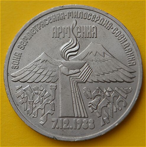 Реверс в центре на фоне гор изображение факела в виде рук, держащих чашу с пламенем. По обеим сторонам факела под горами символично изображены руины - последствие землетрясения. Под факелом дата «7.12.1988». Вверху надпись «АРМЕНИЯ», разделенная пламенем на две части «АРМ» и «ЕНИЯ»