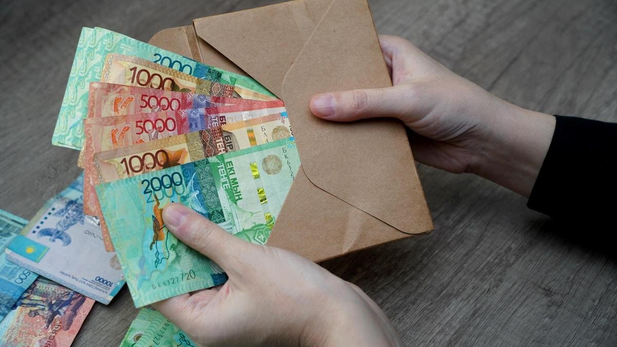    Женщина достает из конверта деньги:NUR.KZ / Владимир Третьяков