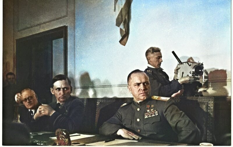 Георгий Петрусов. Маршал Советского Союза Георгий Жуков во время подписания акта о капитуляции Германии. Дата съемки: 8 - 9 мая 1945. Слева направо – Андрей Вышинский, заместитель главнокомандующего союзными экспедиционными силами маршал Королевских ВВС Артур Уильям Теддер. Около камеры – оператор Роман Кармен. Источник: История России в фотографиях
