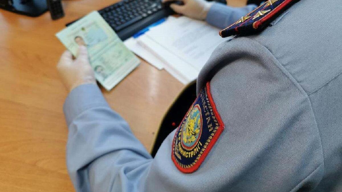    Полицейский проверяет данные в паспорте:polisia.kz