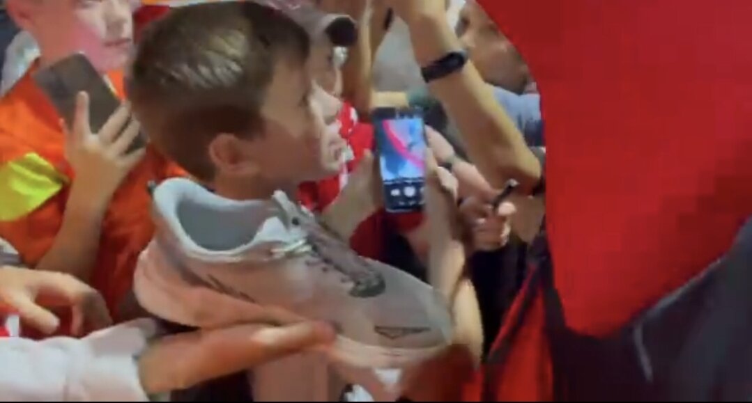 Георгию Джикии протягивают обувь для автографа. Скриншот с видео t.me/amuyzhnek