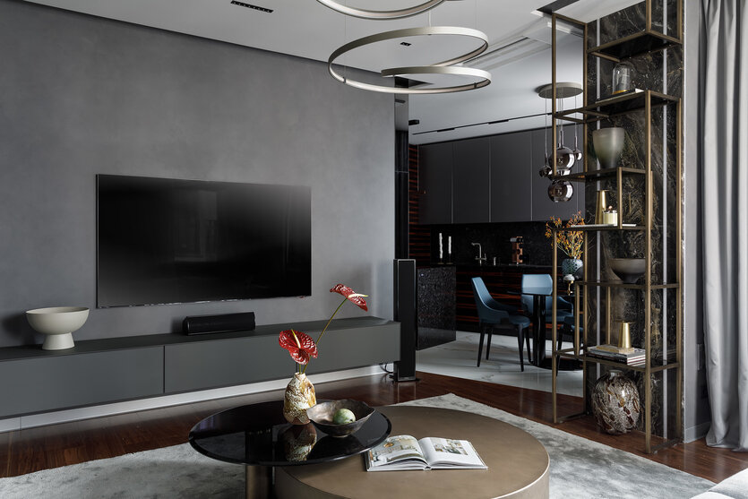 Телевизионная зона. Тумба под TV, Rimadesio. Стены оформлены декоративной штукатуркой Oikos. На полу — паркетная доская Coswick и ковёр из шёлка и шерсти от Limited Edition. Журнальный стол, люстра, Cattelan Italia. На столике — ваза Kartell.