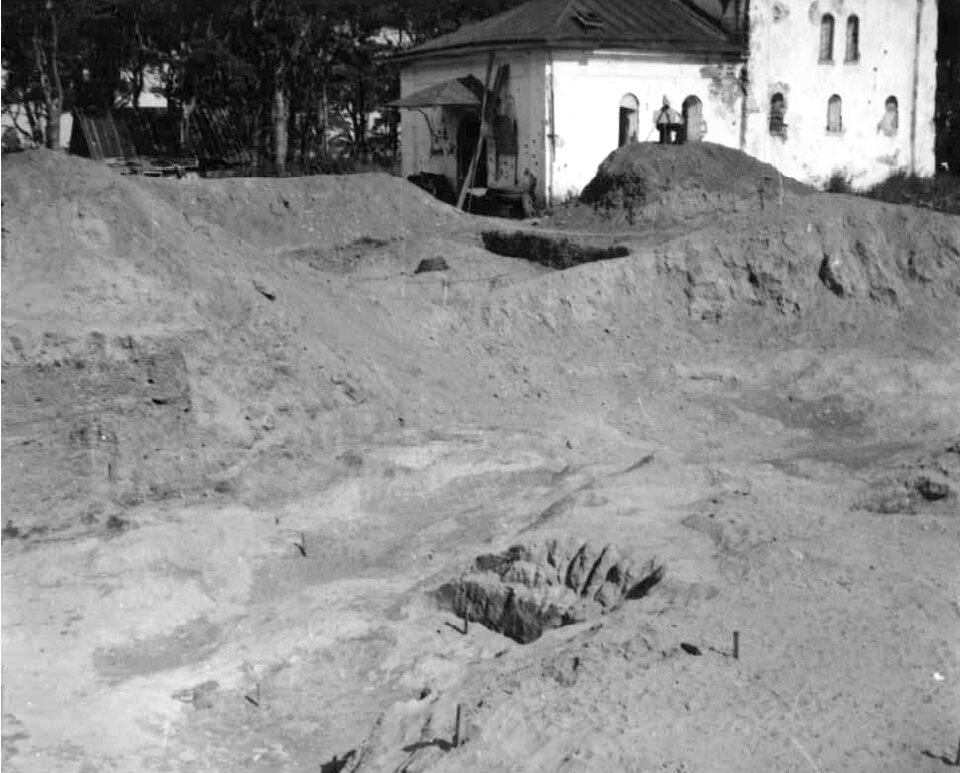 Фото 1951 года руководителя раскопок В.В. Седова с юго-западной стороны церкви. Также виден поздний западный притвор храма, разобранный в ходе последующей реставрации.