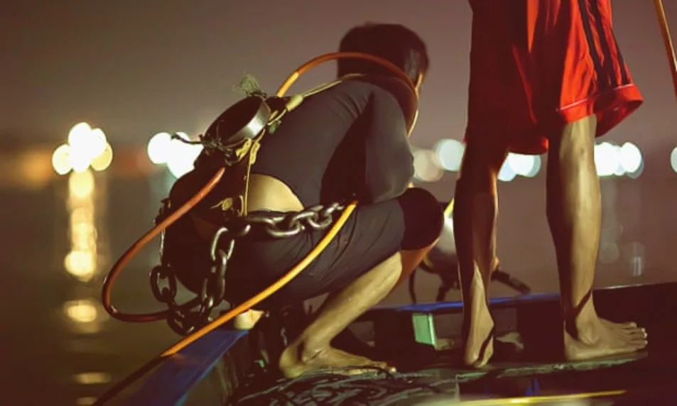 Рыбак готовится к фридайвингу с системой дыхания для кальяна и железной цепью для весового пояса в реке Муси в Палембанге в поисках затонувшего сокровища. Фотография: Изображения предоставлены журналом Wreckwatch