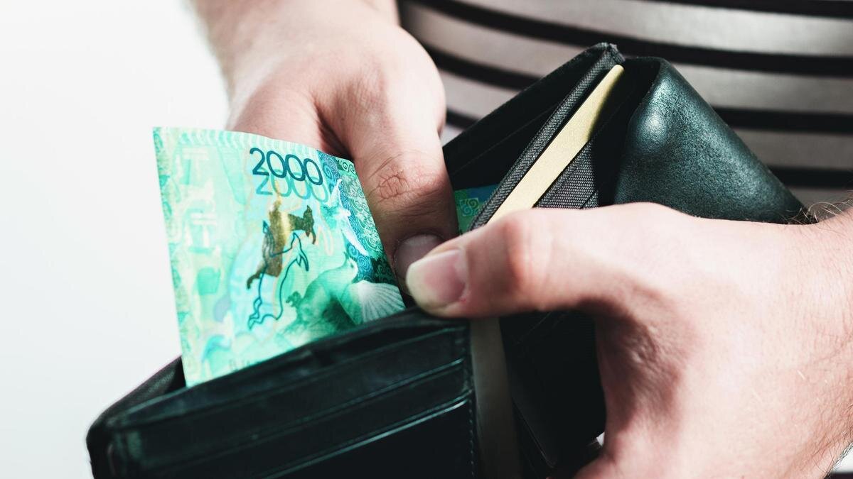    Мужчина держит в руках кошелек с одной купюрой в 2000 тенге:Getty Images/Roman Chekhovskoy