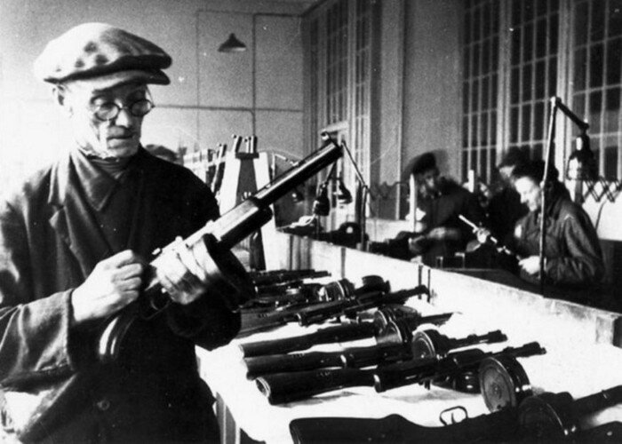 Старый рабочий проверяет оружие, изготовленное детьми на ленинградском заводе, 1944 г.