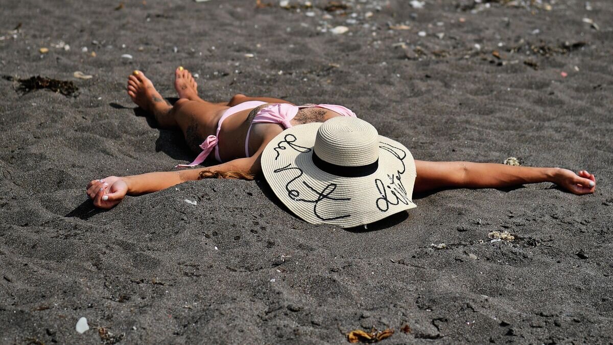    Женщина загорает на пляже Японского моря недалеко от Невельска© РИА Новости / Александр Кряжев