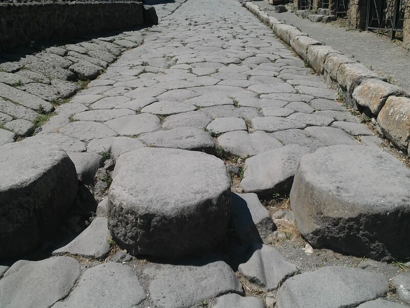 Во время дождя улицу в Помпеях можно было перейти дорогу по этим камням. Тротуары делали высокими для безопасности пешеходов. А еще на улицах города сохранились колеи, выбитые повозками в виде желобов в гладком булыжнике.