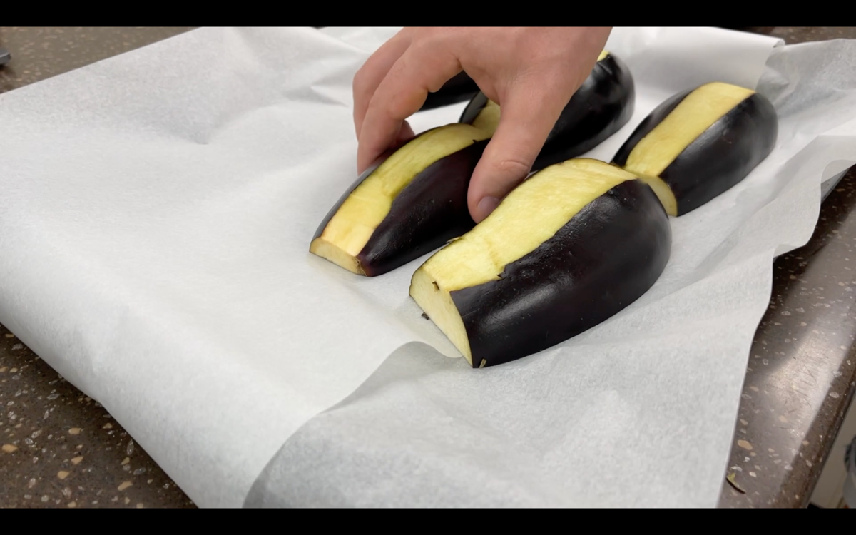 Баклажаны разрезать на пополам,  вдоль. И положить на противень для запекания 