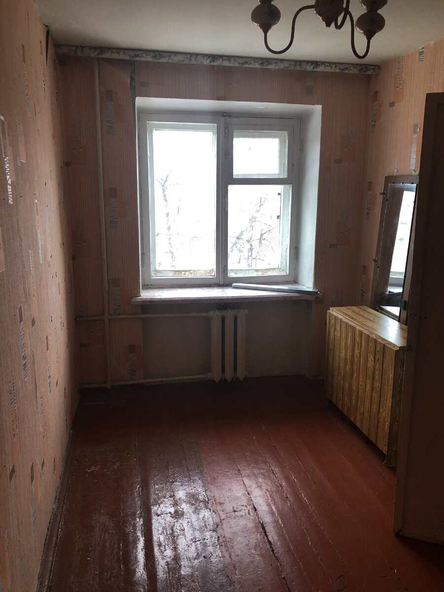 Так выглядит малая комната в хрущевской квартире, на фото обнаруживается алюминиевый радиатор централизованного отопления, а также деревянная рама в оконном проёме.