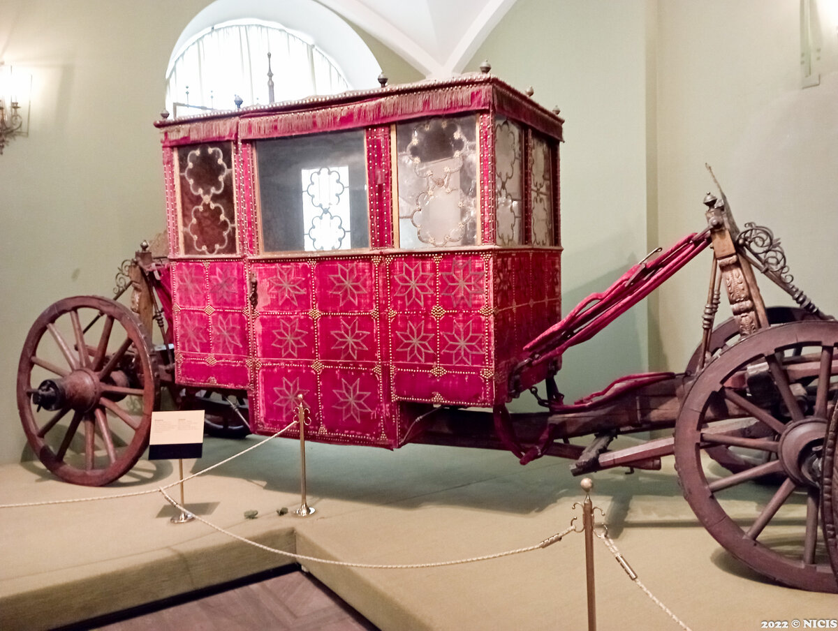 Колымага четырехместная (принадлежала боярину Никите Ивановичу Романову) Россия, Москва.
40-е гг. XVII в.
Мастерские Конюшенного приказа Московского Кремля.
Бархат золотный - Турция. XVII в.
Слюда - середина XVII в.
Стекло - последняя четверть XVIII в(?).
Дуб, береза, бархат, стекло, железо, галун, слюда, олово, медь.
Золочение, резьба по дереву, ткачество, ковка.
Длина:  550,0 см.
ширина:  200,0 см.
высота:  200,0 см