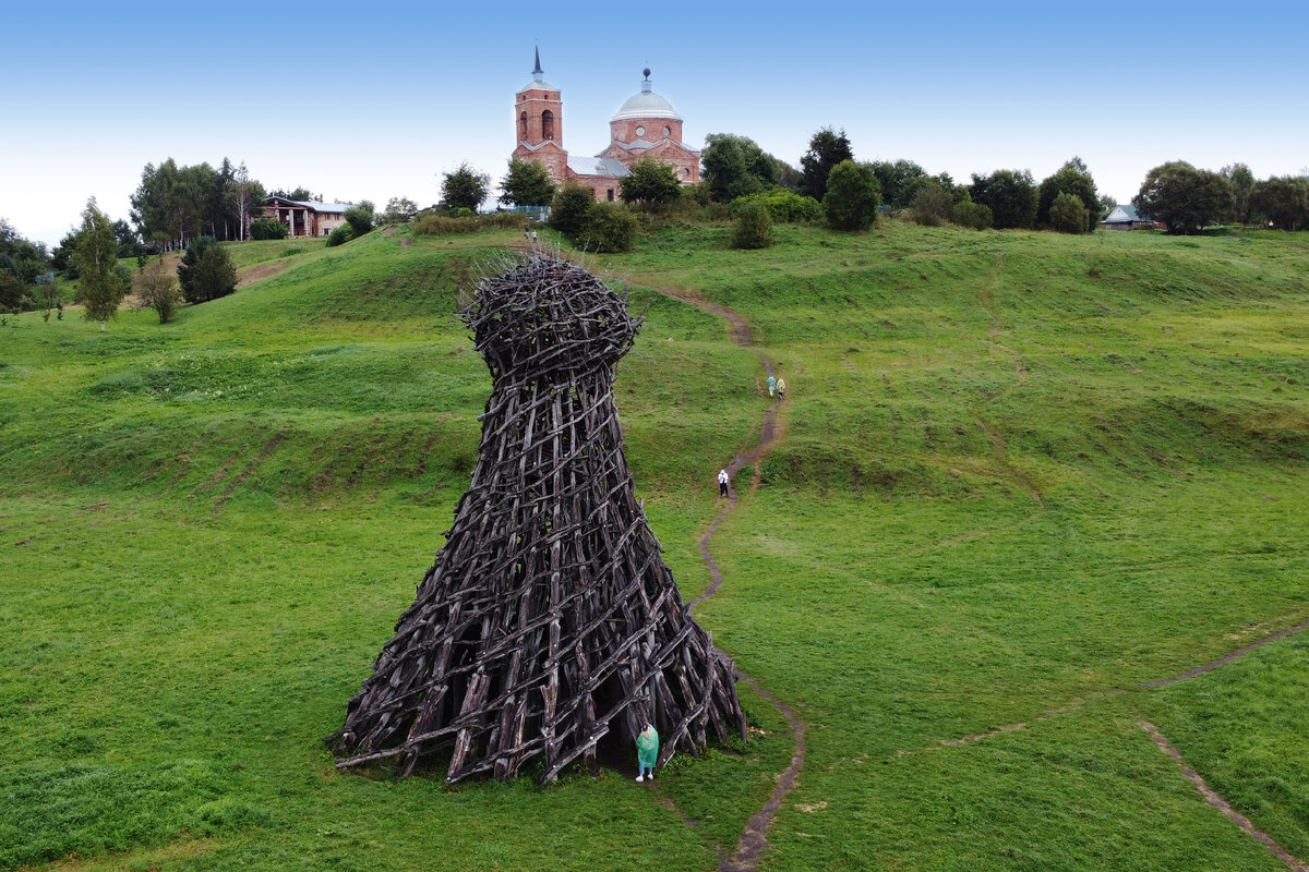 Маяк на фоне Троицкой церкови.  