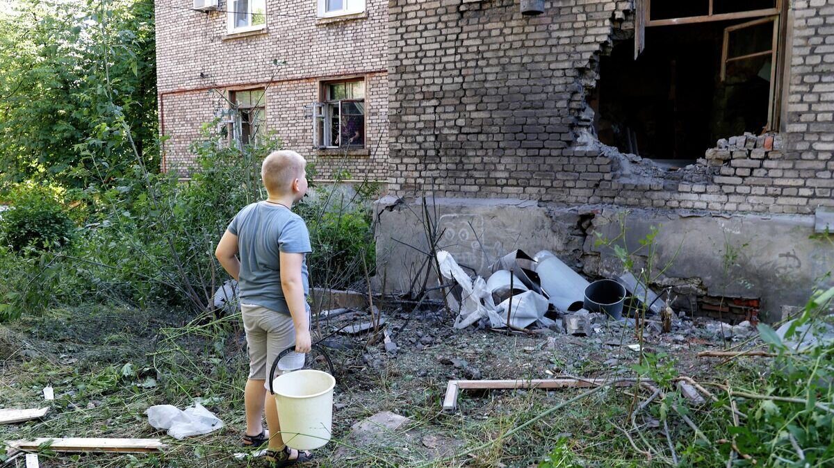    Мальчик возле дома, поврежденного в результате обстрела ВСУ Донецка© РИА Новости / Сергей Аверин