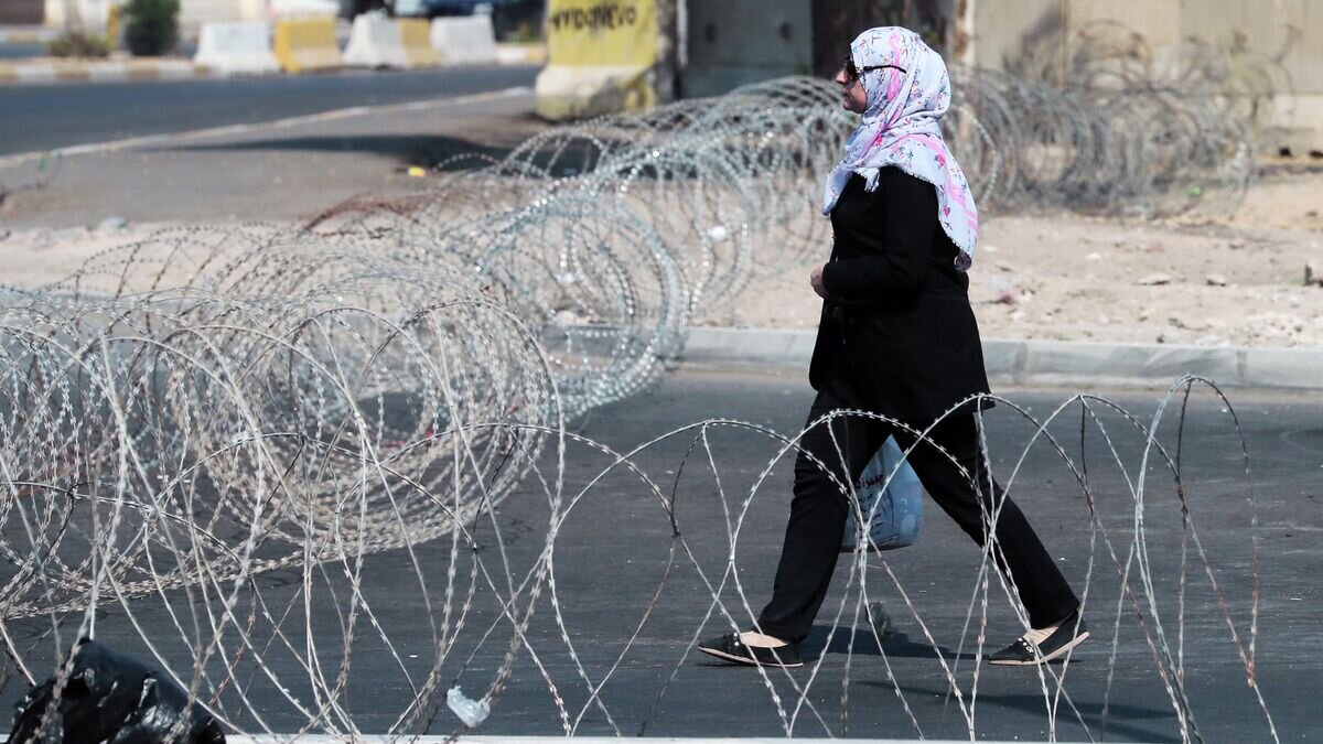    Девушка идет по улице Багдада, огражденной колючей проволокой© РИА Новости / Виталий Белоусов