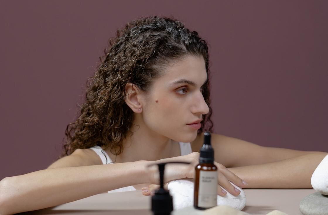    Девушка с кудрявыми волосами и средства для ухода:Pexels