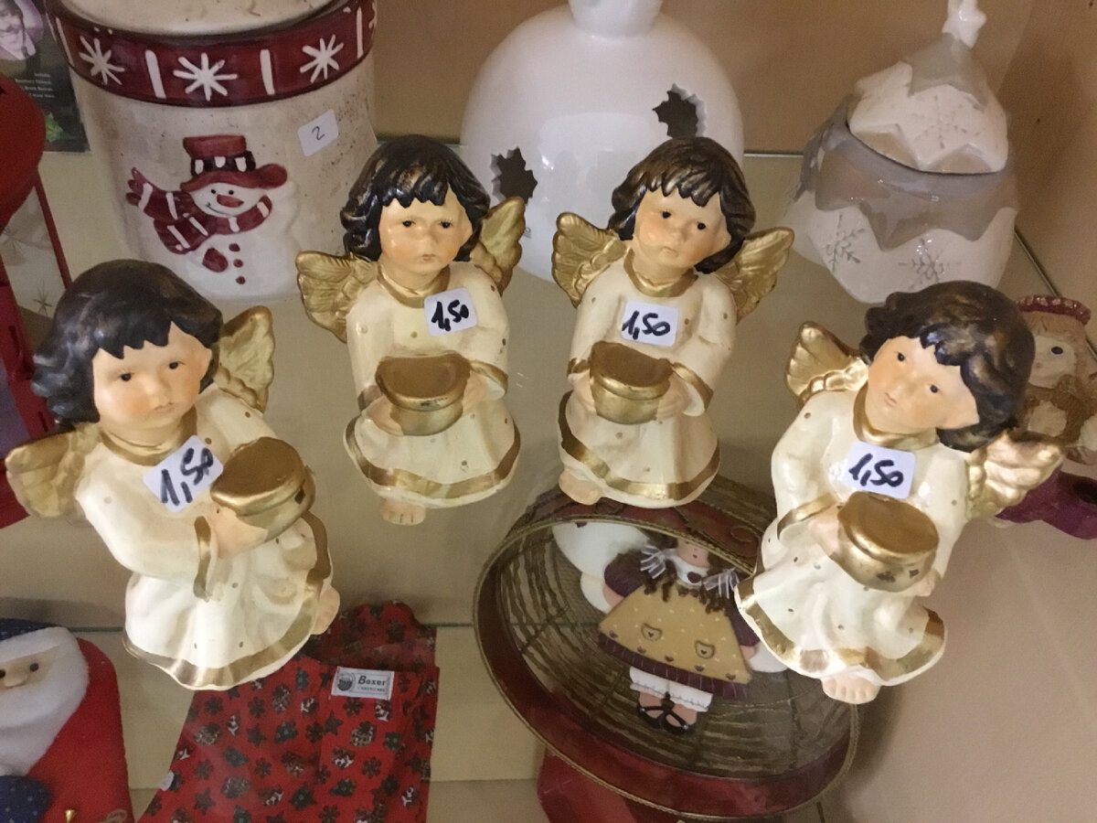 Ангелочки с золотыми коробочками в ручках. В коробочках подарки. Фигурки  стоят на стеклянной полке и снизу просвечивают другие вещицы…