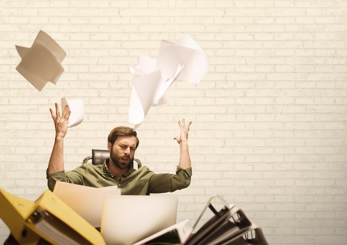 В работе оказался человек. Бросает бумаги. Человек раскидывает бумаги. Брошенные листы бумаги. Разбрасывает бумаги в офисе.