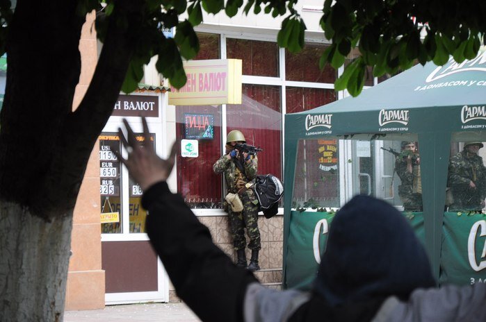 Кафе "Арбат". На фото видно, как военный направляет автомат в сторону безоружных людей. На этом же месте, возле зелёного шатра лежал мужчина с простреленной головой. 