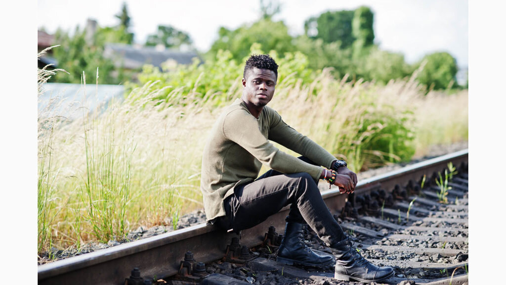    Cool black african american man sitting and posing on railway in the countryside. Александр Шереметьев