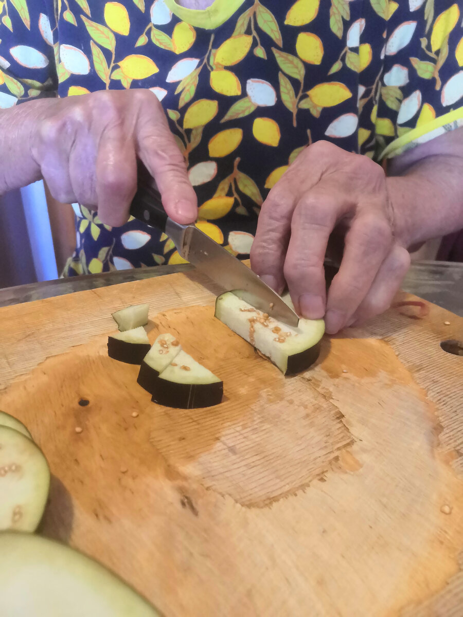 Режет баклажаны для овощной икры.