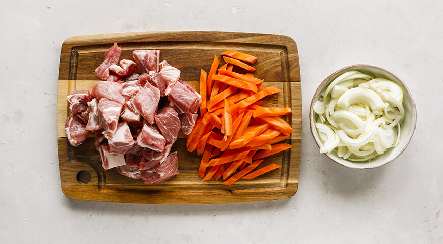 1. Подготовьте ингредиенты для плова. Свинину вымойте, обсушите и нарежьте крупными кубиками. Морковь вымойте, очистите и нарежьте соломкой. Лук очистите и нарежьте полукольцами.