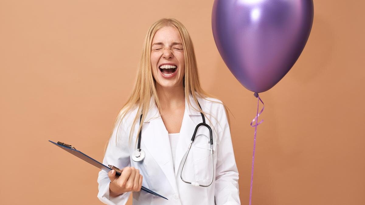    Девушка с шариком и папкой в медицинской форме смеется:Freepik