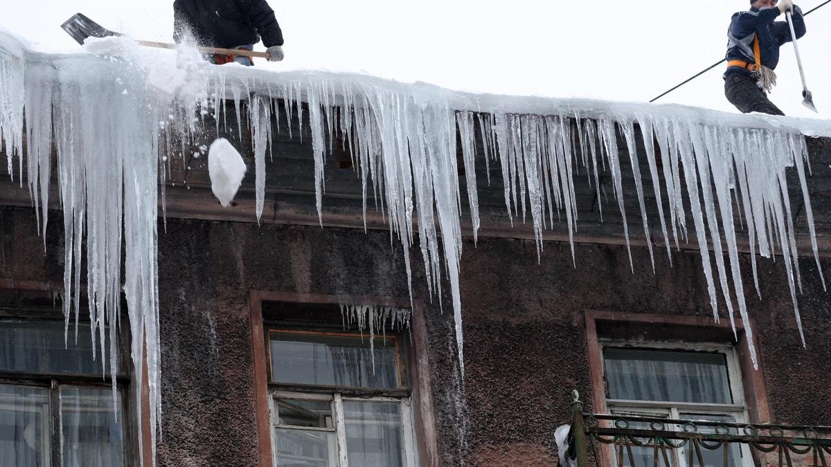    Рабочие сбивают лед с крыши:Kirill Kudryavtsev/Getty Images