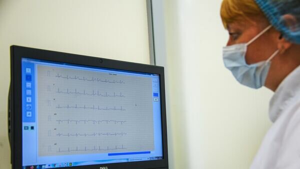    Врач смотрит на электрокардиографию пациента в кабинете "Мое здоровье" © РИА Новости / Евгений Одиноков