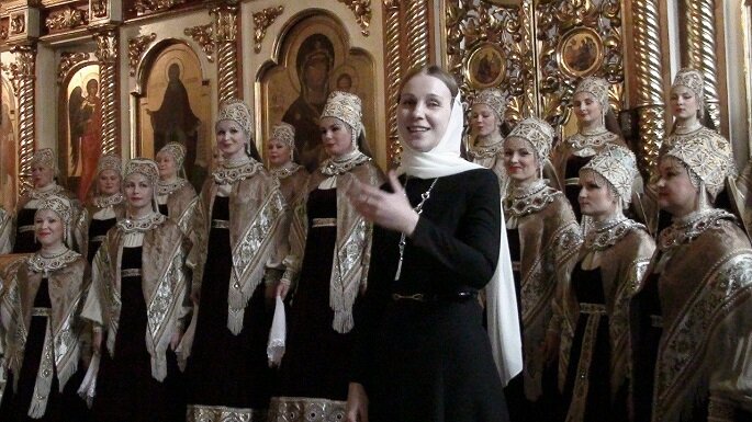 — Я приехала в Северный хор в 2003 году, будучи еще студенткой Гнесинской академии, — рассказывает Надежда Москалева (в то время Миронова). — Нина Константиновна Мешко руководила коллективом почти полвека, которые составили целую эпоху в его развитии. В то время ей было 86 лет, и последние пять лет жизни она была моей наставницей в руководстве Северным хором, где я одновременно была главным хормейстером. Я очень полюбила северную традицию, и чтобы правильно преподавать местный диалект, я отправилась в экспедицию. У них ведь определённая речь, красивая, льющаяся, как ручеек. «Ой девка-то, да пошла-то туда, да по праву-то руку…». В северном регионе говорят с «токаньем», «оканьем», «цеканьем». Вот, например, северная камаринская «Прялица», которую мы поем и с ансамблем «Подворье», звучит так: «сарафанчик раздуваеЦе, ко мне милый приближаеЦе». Такой у них мягкий говор. Это была крайне интересная экспедиция, что называется, «на прорыв». 

В гостях у носителей северного фольклора
— Первое, что я услышала, когда приехала на Пинегу — это совершенно непонятный язык. Сначала я не разобрала ни слова, потом потихонечку стала вникать, записывать, перемещаться из деревни в деревню, от одной исполнительницы к другой, искать образцы народных напевов, — рассказывает Надежда Москалева. – К сожалению, многоголосия там уже нет, я записывала отдельных исполнителей, но это тоже очень интересно. Например, в селе Сура Архангельской области Пинежского района, это родина святого Иоанна Кронштадтского, я жила у бабушки Анны Ивановны. Она парила меня в бане и потом учила играть на балалайке, не по классическому, по классическому я умела, а по- фольклорному. Фольклор имеет свой строй, балалайка для такой игры по-другому настраивается. Интересный исполнитель был Михайлов, из села Холмогоры в Архангельской области. Я переняла у него уникальные наигрыши на балалайке, которые больше нигде не слышала.

Надежда Москалева изучала старинные северные обрядовые песни, техники исполнительства, подлинные костюмы. Местные люди жили замкнуто, не каждую исследовательскую экспедицию из Москвы принимали, но ее, прибывшую из Архангельска, приняли как свою и с удовольствием делились песнями.

— В нашей традиционной культуре существовала методика изустной работы с голосом, то есть она передавалась из уст в уста. И она дошла до нас с помощью записей, собственных исследований. Но, когда я, например, изучала, как поют бабушки, клала им во время пения руку на живот, чтобы понять, как они добиваются этого мощного звука, они очень надо мной смеялись, потому что у них нет искусственных приемов. Они просто садятся рядышком и поют, тонко прислушиваясь друг к другу.

 Сохранение культурного наследия
Надежда Москалева участвовала более чем в тридцати этнографических экспедициях по дальним уголкам Севера и Юга России. Она отмечает, что в настоящее время традиционное полифоническое исполнение фольклора практически утрачено. Однако в ХХ веке оно еще существовало, и этномузыкологи провели большую работу по записи песен в многоголосом исполнении бабушек. Изучение этого явления ведется до сих пор. Искусству расшифровки архивных записей Надежда Львовна училась у основателя практической и экспериментальной фольклористики Андрея Сергеевича Кабанова, который посвятил свою жизнь собирательству, исследованию и сохранению народной песни.

— Тут не получится записать каждую исполнительницу отдельно, в вакууме, потому что она должна слышать остальных, чтобы импровизировать. Применялась многоканальная запись, когда все бабушки поют вместе, но возле каждой стоит свой микрофон, и все это записывалось на бобинный магнитофон. На такой записи фоном слышно всех, а один конкретный голос — близко. Исполнительниц могло быть до 9 человек. А мне при работе с такой записью надо было каждую из них расшифровать, потом все это соединить, такая работа занимает до полугода. И в результате получается сложная, невозможная для сценического исполнения песня. Даже Северный хор, профессионалы, не могут с этим справиться, потому что это — импровизация. Чтобы исполнять традиционные песни на сцене, мы их аранжируем для современного хора, сохраняя слогоритмическую структуру местных напевов.

На сцене и в быту
В настоящее время Государственный академический Северный русский народный хор является одним из лучших коллективов, хранящих традиции регионов России. В 2014 году хор принимал участие в культурной программе Зимних олимпийских игр в Сочи, представив уникальный северный фольклор, его самобытный диалект, сложные образцы многоголосия и народного танца. За достойную подготовку коллектива к участию в международной программе Надежда Москалева, как главный хормейстер, была награждена медалью и грамотой президента России.

И все же фольклор – явление не сценическое. Эти песни слагали наши предки, заключая в их текстах народную мудрость. Исполняя их в песенном кругу, люди давали выход эмоциям при помощи мощного инструмента – собственного голоса. Истоки этого явления и формы его существования в современном мире – темы наших следующих публикаций.

Автор статьи
Елена Карасева
Газета 'Щербинский вестник"
2022

