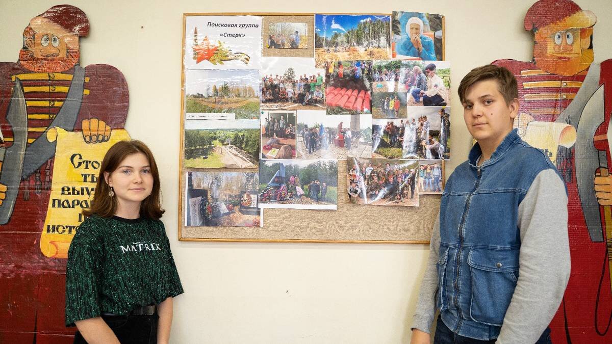    Участники поискового отряда школы № 1354 «Вектор» Майя Кашперова и Михаил Гуров у стенда с фотографиями благоустроенного мемориала в Тверской области / Фото: Анна Темнышова / Вечерняя Москва