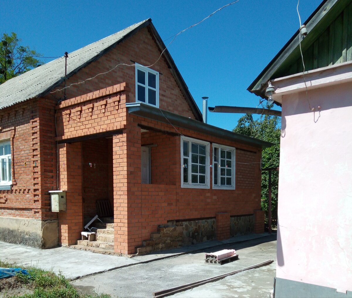 Дом из красного кирпича пустует, а мы живём напротив в гостевом доме. На фото.