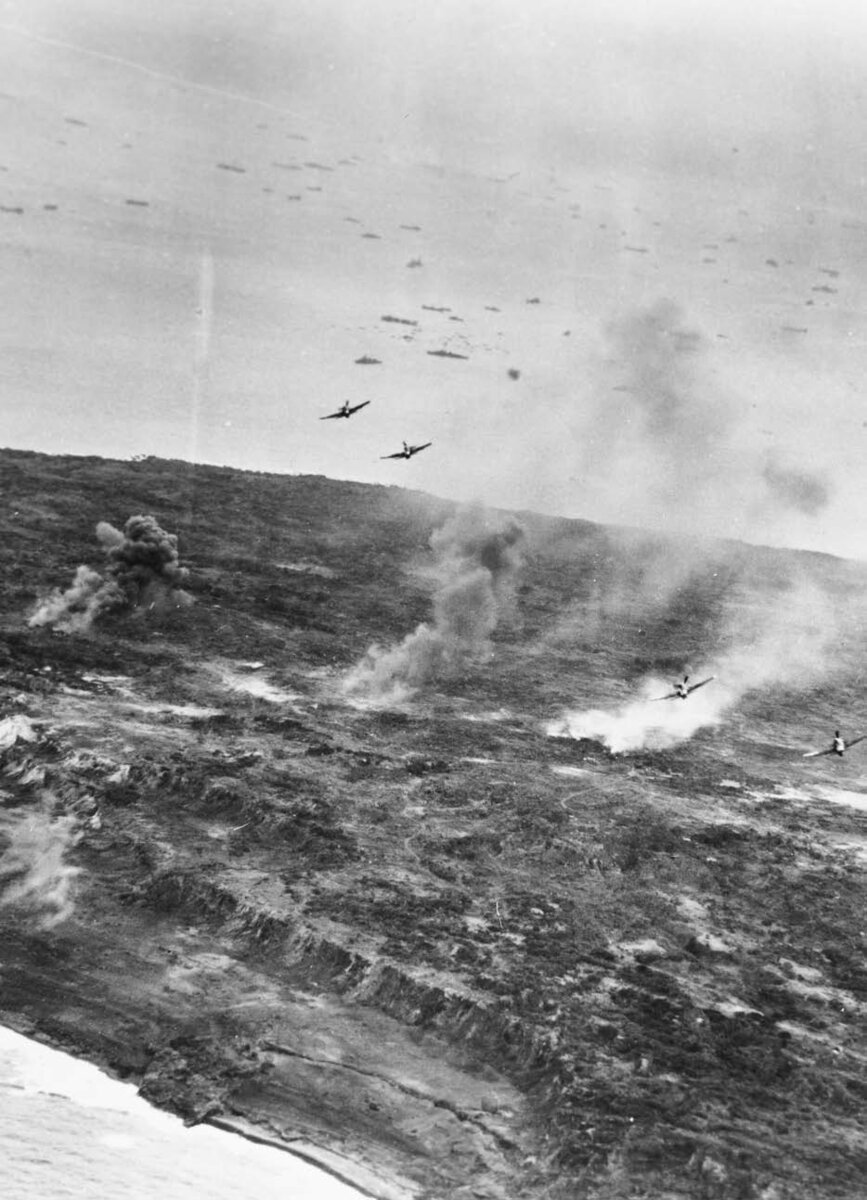 Иводзима. Четыре бомбардировщика-торпедоносца Grumman Avenger сбрасывают свои бомбы в районе между аэродромами № 1 и 2. На переднем плане видны скалы карьера с видом на район Ист-Боут. (Национальный архив)