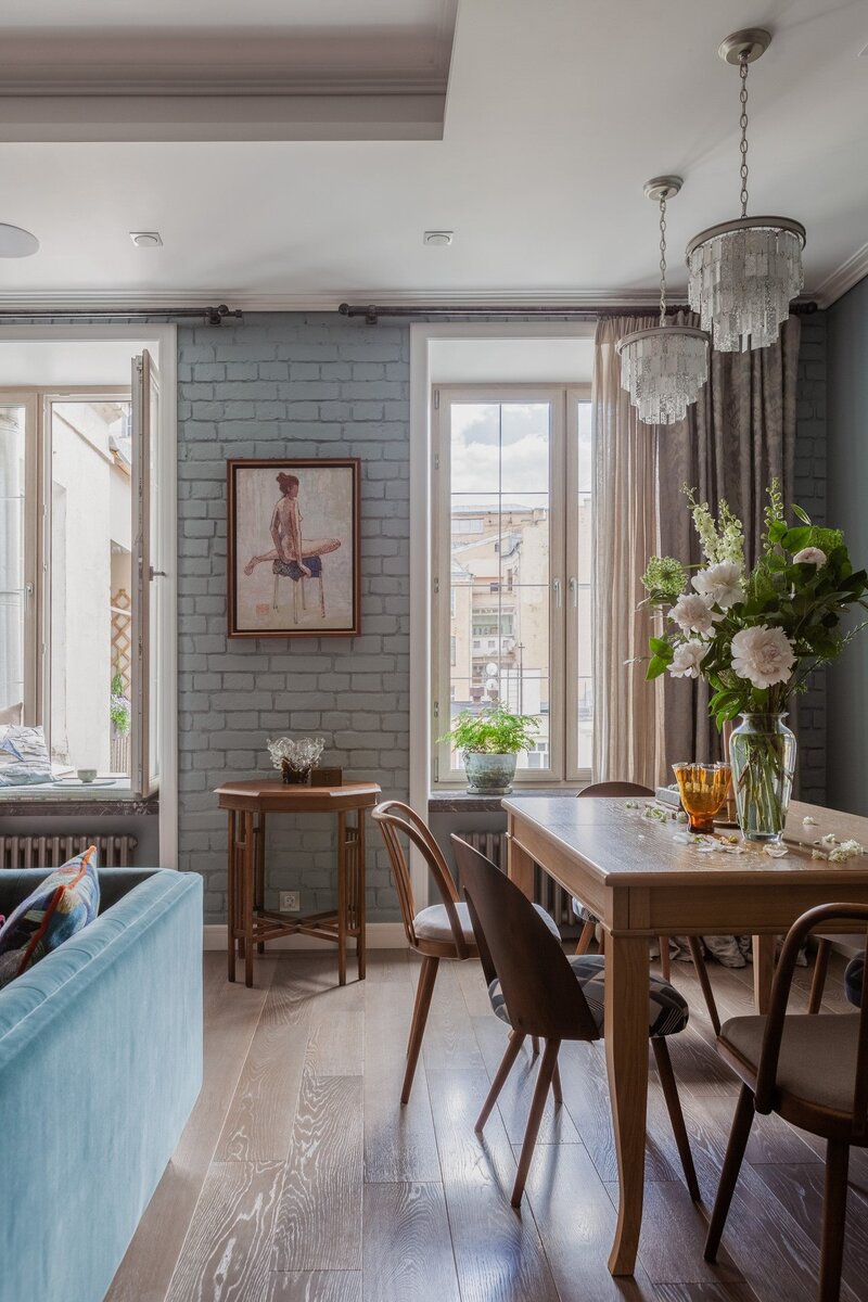 Характер интерьера определяют разные оттенки синего и бирюзы. За «дух истории» отвечают винтажные стулья, старинная кирпичная кладка и инженерная доска на полу.