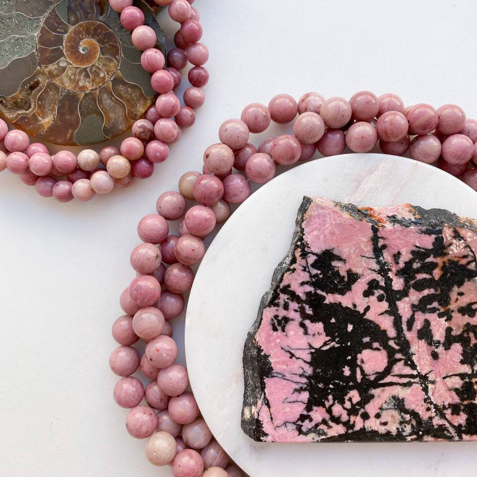 Бусины из мусковита с альбитом и кварцем и срез настоящего родонита.