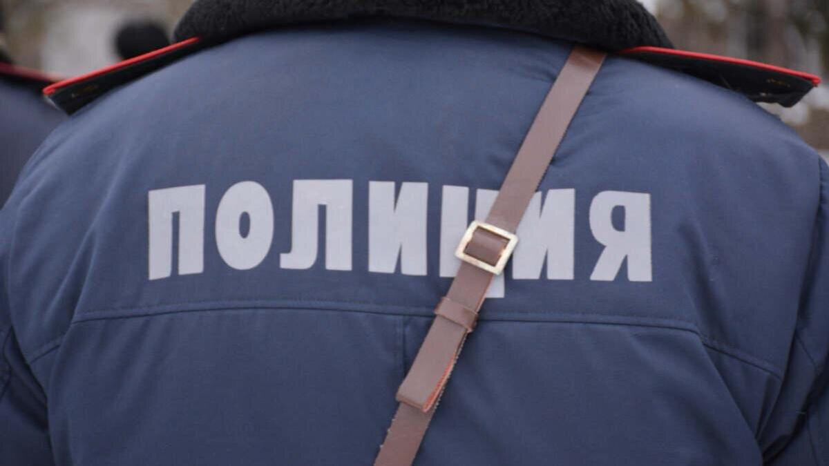    Полицейский в форме стоит спиной к фотографу:polisia.kz