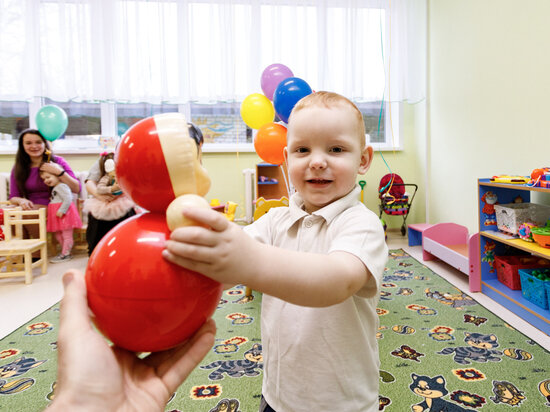     Ребёнок принимает из рук взрослого игрушку / Вадим Боченков