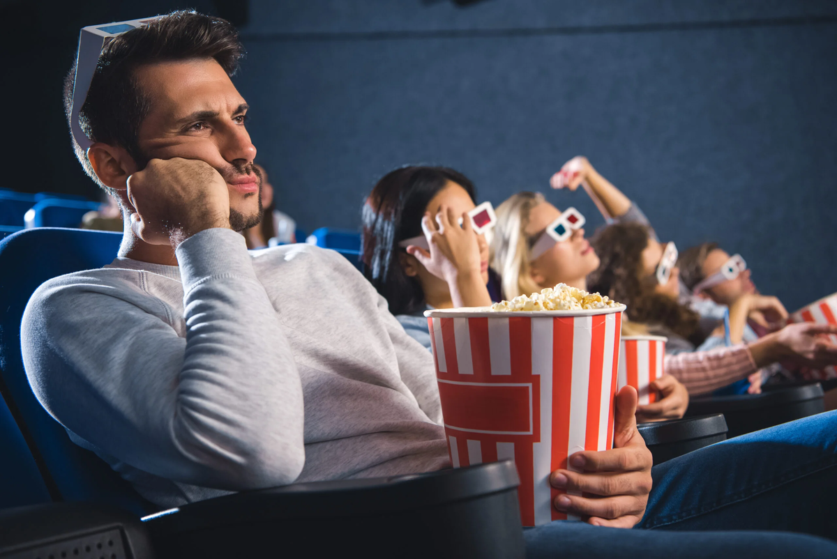 Сеанс кинофильма. Зритель с попкорном. Попкорн в кинотеатре. Человек в кинотеатре с попкорном.