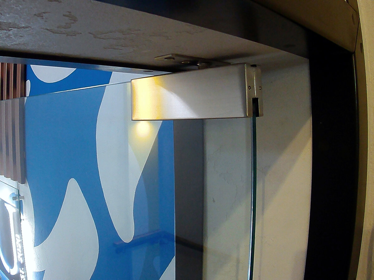 Полуторастворчатая стеклянная маятниковая дверь в кафе под заказ в Нижнем Новгороде от Компании Грифон. 