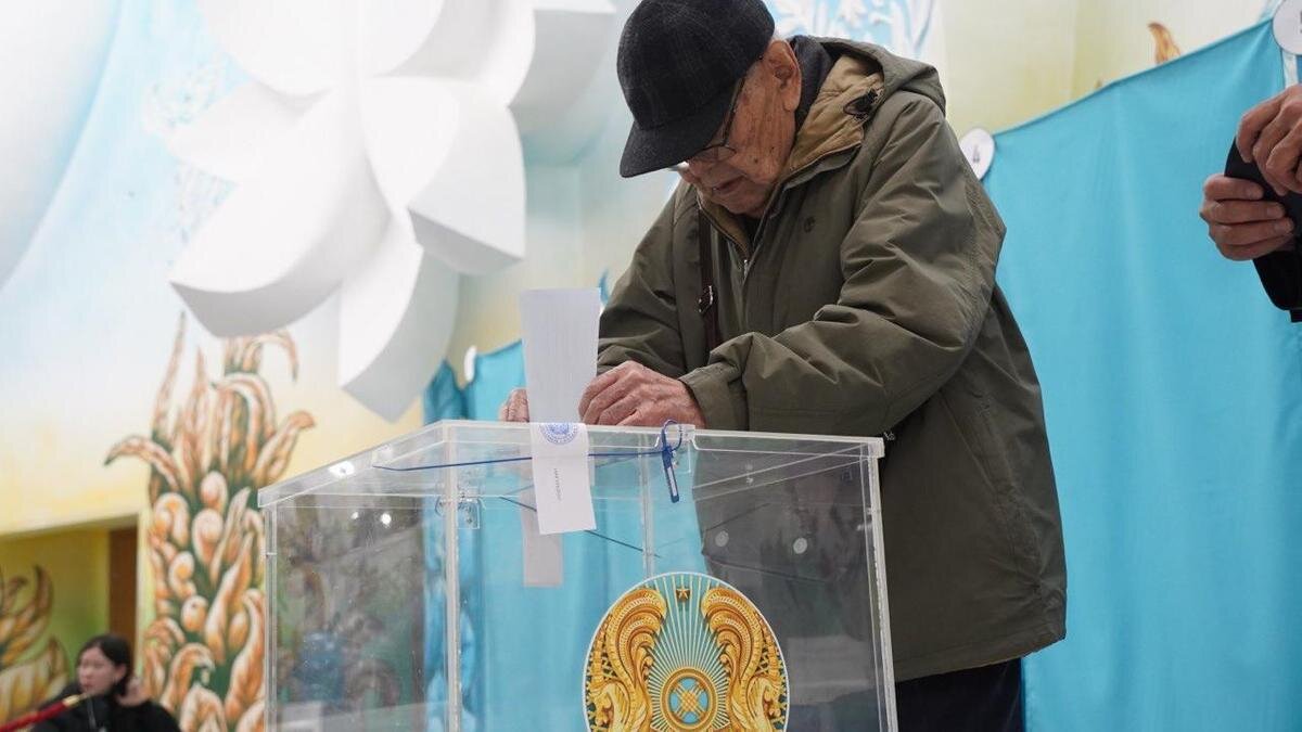    Человек кидает бюллетень в урну для голосования:NUR.KZ / Владимир Третьяков