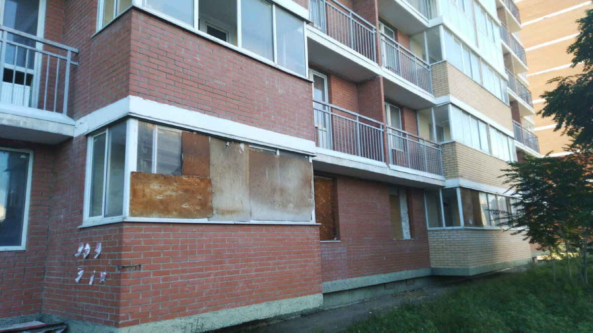 Первые этажи незаселённого дома с фанерой вместо стёкол