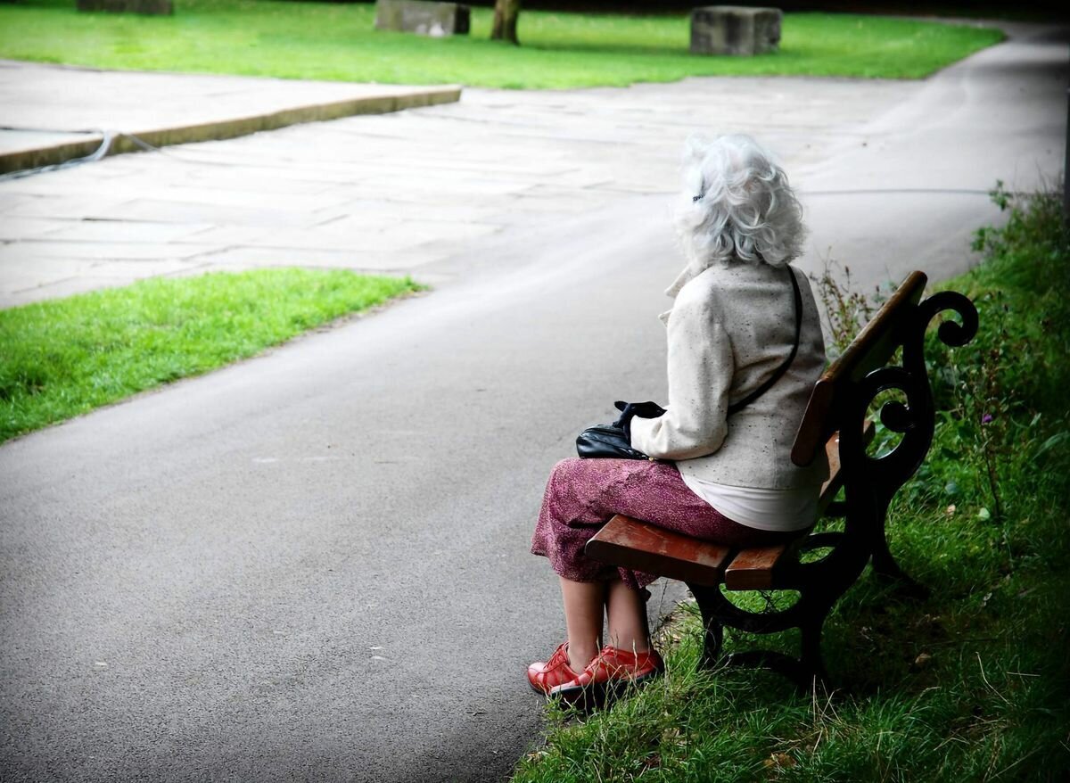 Пожилая женщина на скамейке в парке