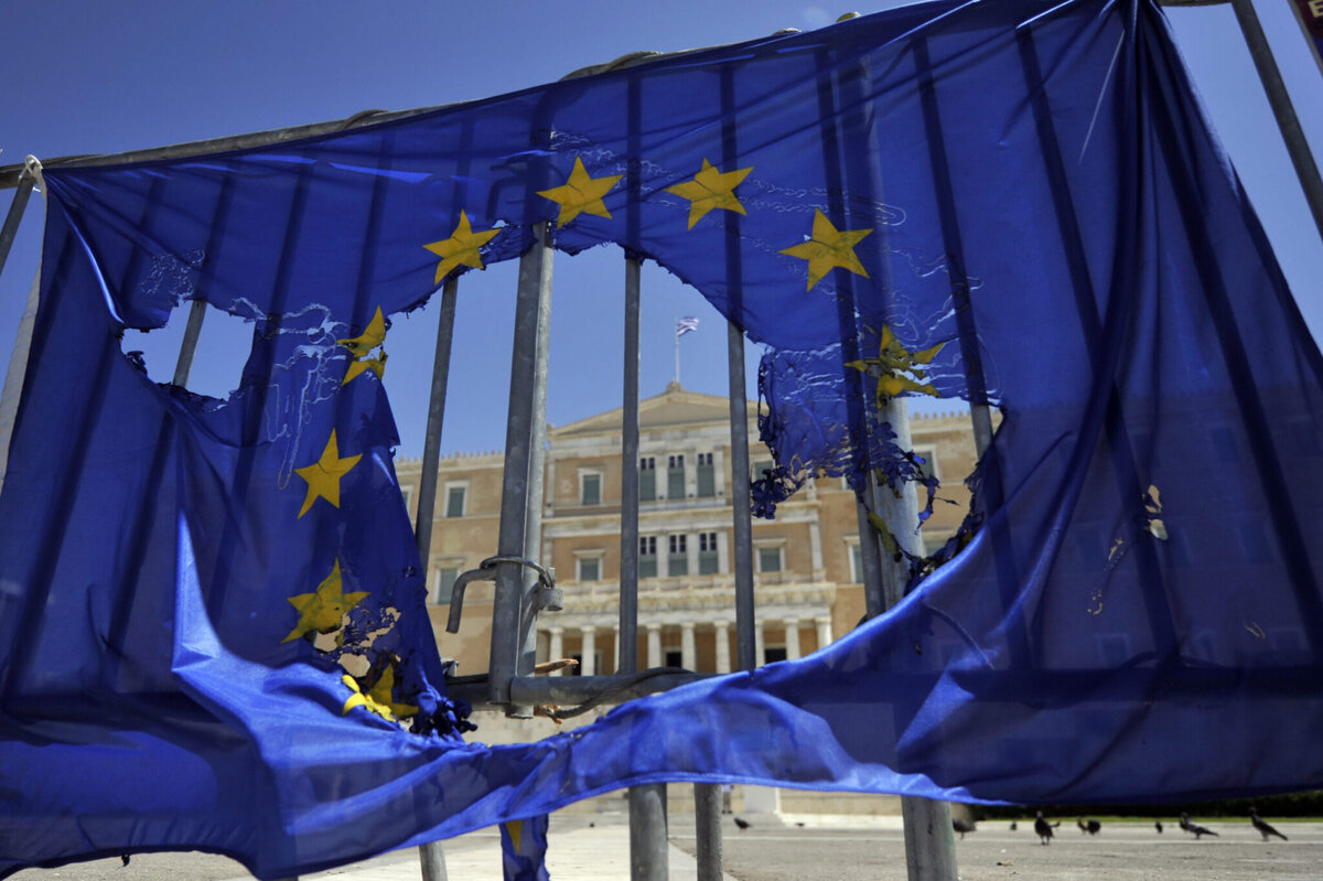    A burned EU flag hangs on the barriers protecting the Greek parliament in Athens on May 1, 2013. Greece's two main unions called a general strike against prolonged austerity on May 1, with protests by unions, students and workers. AFP PHOTO/ LOUISA GOULIAMAKI (Photo credit should read LOUISA GOULIAMAKI/AFP/Getty Images) editor