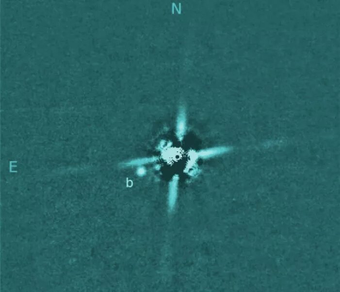 Прямое изображение, полученное телескопом Subaru недавно обнаруженной экзопланеты 2M0437b, газового гиганта, который вращается вокруг звезды в 417 световых годах от Земли. Чрезвычайно яркая родительская звезда была в основном удалена методами обработки изображений; четыре «шипа» - артефакты, создаваемые оптикой телескопа. (Изображение предоставлено телескопом Subaru)