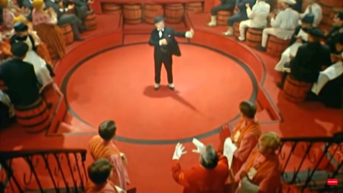 Условные декорации, яркий фон, контрастные фигуры. Угадывается арена цирка. Представление внутри представления. Кадр фильма "Интервенция", скриншот. 