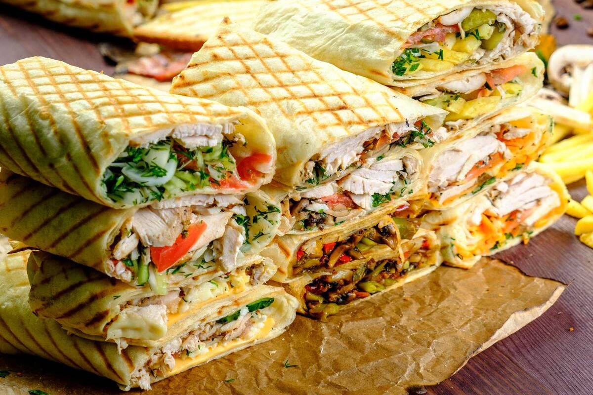 В позапрошлом веке в странах Ближнего Востока начали готовить сытное и вкусное блюдо. В лаваш или питу заворачивали рубленое мясо, обжаренное на гриле, овощи с приправами и соусом. Получалось быстро и питательно. Со временем арабский фастфуд стал популярен во всем мире. У нас он продается под названием шаурма. Польза и вред этого блюда активно обсуждаются как потребителями, так и диетологами. 
