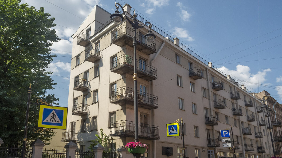 Необычные дома Петербурга 
"Слеза социализма"

На рубеже 20-х и 30-х годов прошлого века на углу улицы Рубинштейна и Графского переулка, который тогда назывался Пролетарским, построили необычное здание. Официально дом назывался «Дом-коммуна для инженеров и писателей». Авторы планировали сделать эксперимент и создать новое по меркам того времени жилье. Группа молодых инженеров и писателей возвела его на паях, то есть «вскладчину». Автором выступил Андрей Оль.

В шестиэтажном здании размещалось 52 квартиры, от однокомнатных до четырехкомнатных (трехкомнатные квартиры были двухэтажными). Имелись общие для всех жильцов комнаты отдыха, детский сад, душевые, библиотека-читальня, столовая на 200 мест с кухонным блоком и парикмахерская. На террасе пятого этажа солярий, площадка для игр и оранжерея. Санузлы были общими, по одному на каждом этаже. Высота потолков вполне достойная— 2,8 м.

Предполагалось, что жители всех 52-х квартир должны были принимать пищу в одной общей столовой. Жильцы сдавали свои продовольственные карточки администрации, ежемесячно вносили плату и получали трехразовое питание. Работали в кухне специально приглашенные сотрудники Нарпита. И только в буфете, где можно было купить десерт, дежурили женщины, живущие в доме. Отдельных кухонь, как, кстати, и санузлов, не существовало.

Таким виделся творческой молодежи того времени коммунистический рай, а вера в светлое будущее была главной религией страны. «В доме было шумно, весело, тепло, двери квартир не запирались, все запросто ходили друг к другу, - вспоминала поэт Ида Наппельбаум, которая тоже жила в Доме. Иногда внизу в столовой устраивались встречи с друзьями, с гостями приезжали актеры после спектаклей, кто-то что-то читал, показывали сценки, пели, танцевали. В тот период, впервые после суровой жизни последних лет военного коммунизма, стали входить в быт советских людей развлечения, танцы, елки...».

Но… что-то пошло не так. Прогрессивный социалистический быт будущего ленинградцы не оценили: плохая звукоизоляция, протекающие трубы, конфликты из-за общего санузла и невозможность поесть в своей квартире. Не случившийся коммунальный рай в народе окрестили «Слезой социализма».Позже квартиры перепланировали, в каждой появились ванная и кухня. А в 1990-е и вовсе стали объединять, создавая многокомнатные элитные объекты.

Сегодня дом продолжает жить насыщенной жизнью на улице, превратившейся в одну из самых оживленных ресторанных магистралей города. Говорят, дом населяют в основном потомки первых его жильцов. А ими в свое время были Ольга Берггольц, Ида Наппельбаум, Павел Евстафьев, Николай Костарев, Петр Сажин, Александр Штейн и многие другие, чьи имена гремели в 1930-х, но оказались забыты сегодня.
