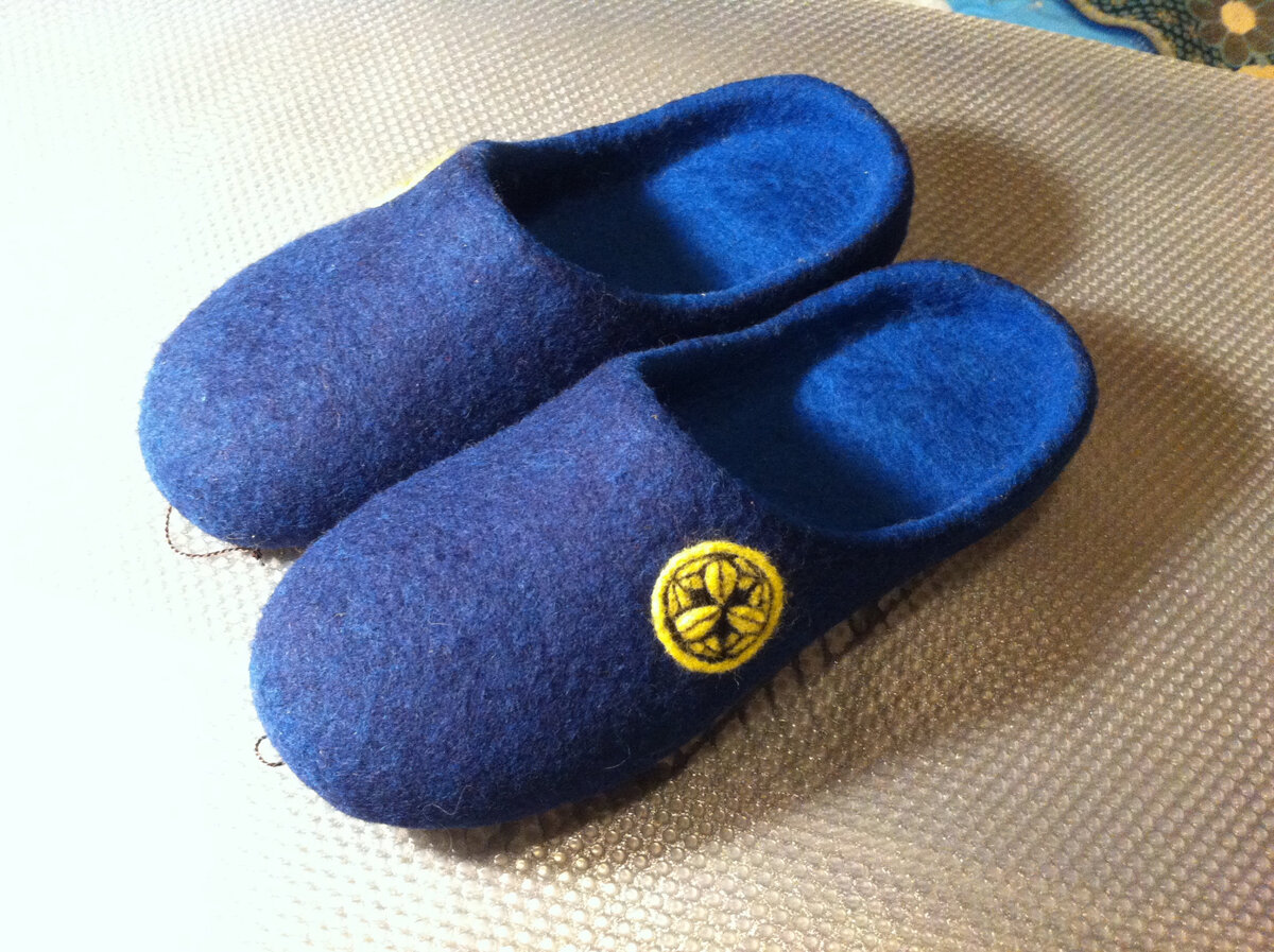 Вариант декорирования тапочек в серии или с точной передачей рисунка символов. Я для этого изготавливаю шаблон из обычной бумаги. И точнее, этот шаблон вырезается из распечатанного рисунка с прорезанием базовых линий. В данном случае, вырезается только один лепесток рисунка и по мере исполнения мастер поворачивает шаблон по кругу, исполняя в вырезанном лепестке всех лепестковых частей. Для рисунка используется игла для фильцевания. Способ сухого валяния.